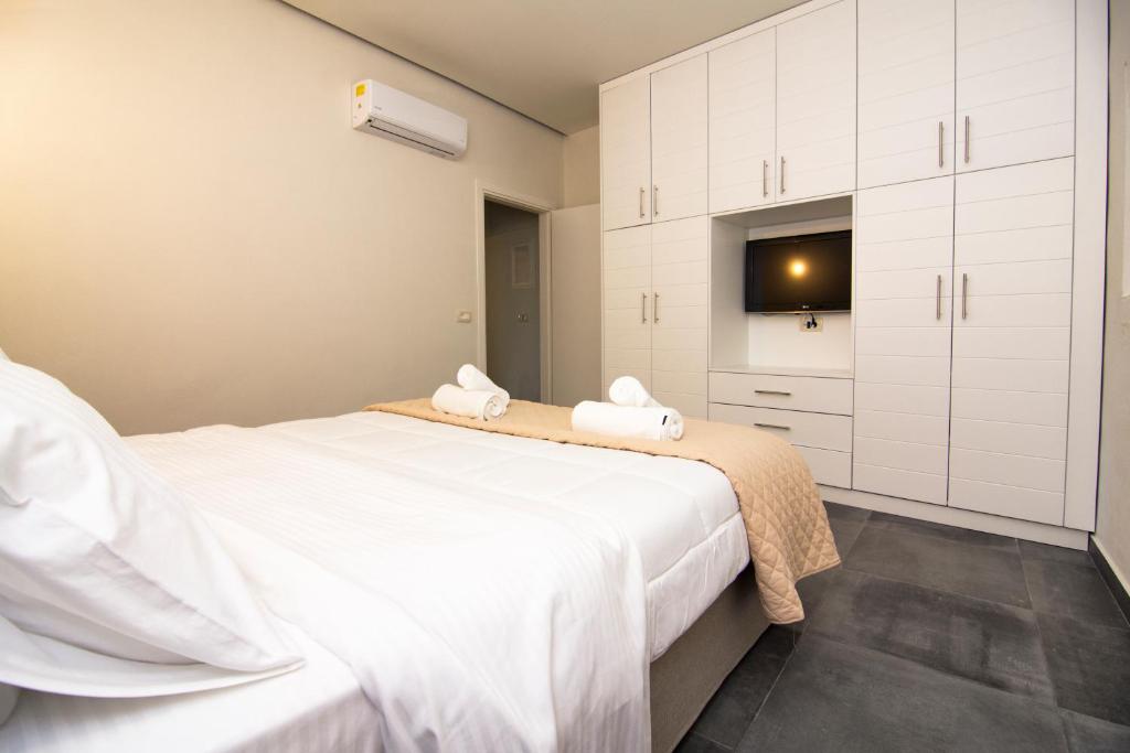 a bedroom with two beds and a tv on the wall at Acrothea Perdika in Perdika