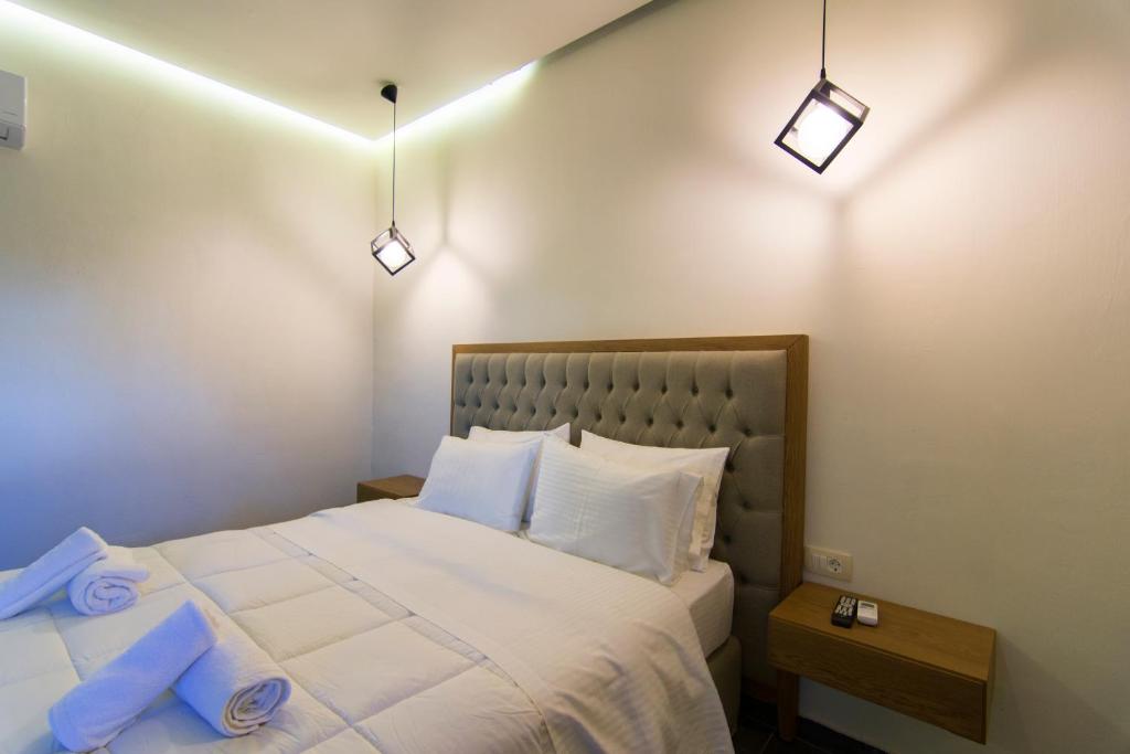 a bedroom with a white bed with two blue pillows at Acrothea Perdika in Perdika