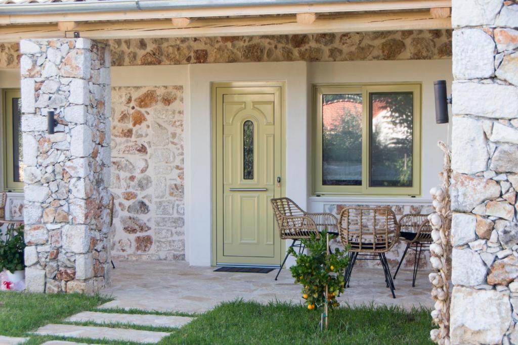 a house with a yellow door and chairs on a patio at Acrothea Perdika in Perdika