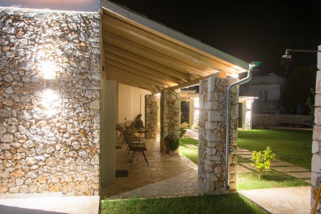 a patio with a stone wall at night at Acrothea Perdika in Perdika