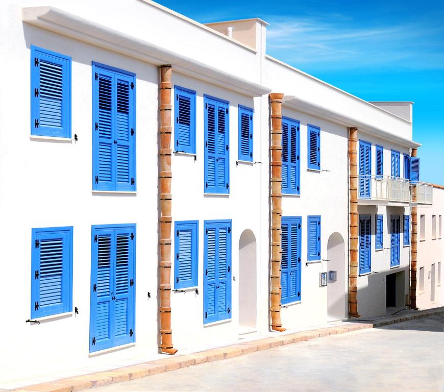 un edificio blanco con persianas azules en Cala del Porto Residence, en Marettimo