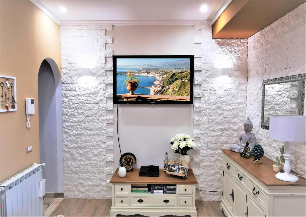 a living room with a tv on a wall at Casa Le Maioliche in Giardini Naxos