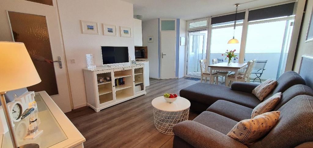 un soggiorno con divano, TV e tavolo di Strandläufer-G13 a Heiligenhafen