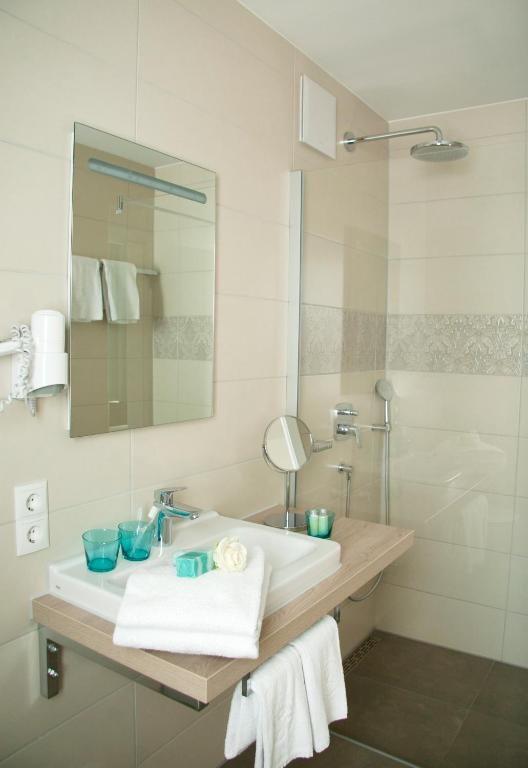 a white bathroom with a sink and a mirror at Hotel Claro Garni in Eitting