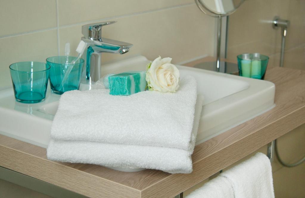 a bathroom sink with towels and a flower on it at Hotel Claro Garni in Eitting