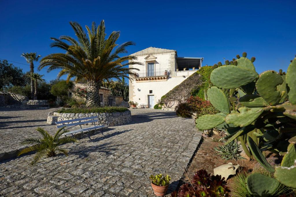 a house with a palm tree and a cobblestone street at Villa Cammarana in Ragusa