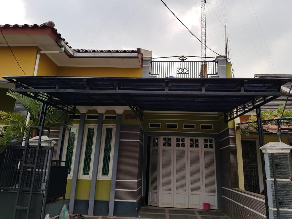 a small yellow house with a black awning at Kartika Guest House Cianjur in Tjiandjur