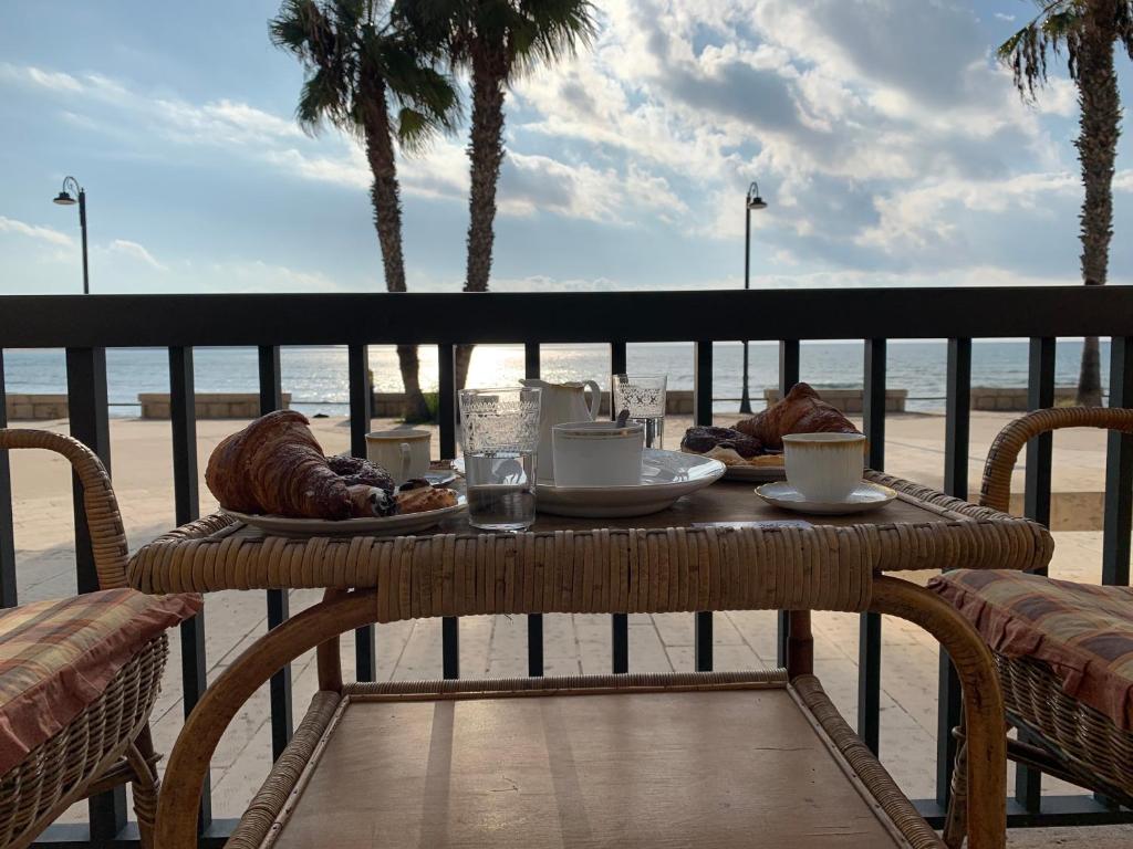 サンピエリにあるTrono a mareのビーチ付きのバルコニーにテーブルと食べ物