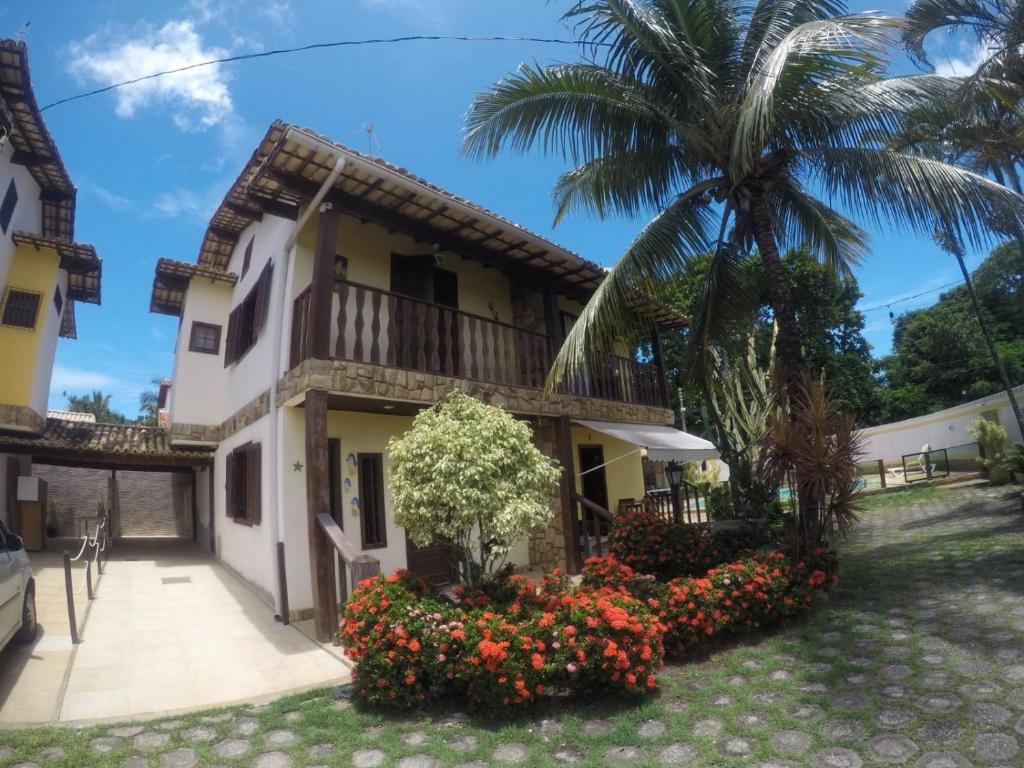 a house with a palm tree and flowers at Paraíso Casa de Praia em Saquarema in Saquarema