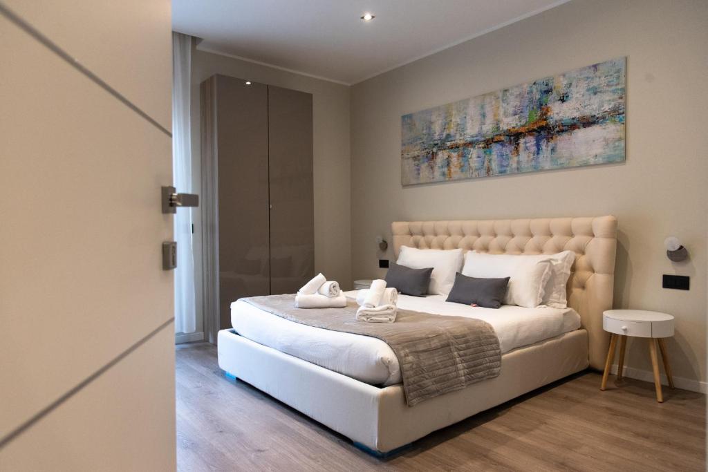 XXIV Domus Luxury Suites في روما: غرفة نوم بسرير ابيض مع لوحة على الحائط
