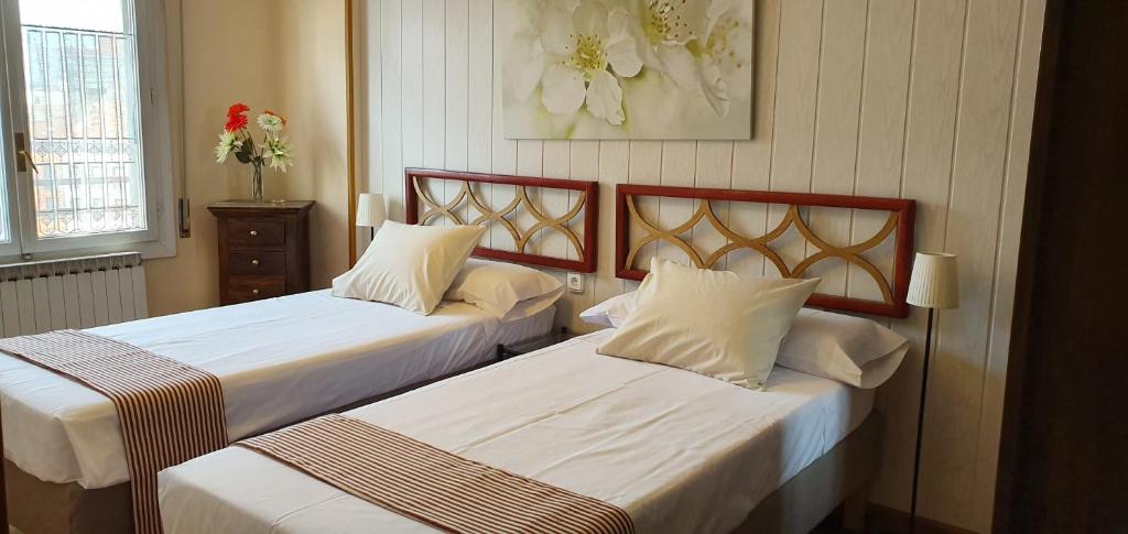 two beds in a hotel room with white sheets at La Pintada 3.0 in Valladolid