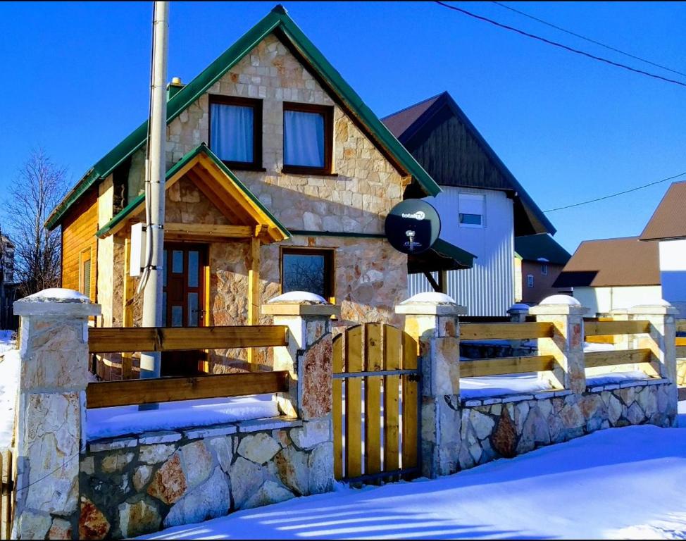 ein Steinhaus mit einem Holzzaun im Schnee in der Unterkunft Guesthouse MG in Žabljak