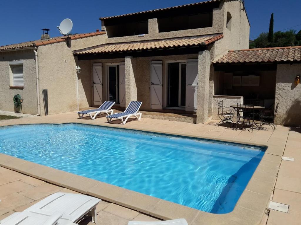 - une piscine avec 2 chaises et une maison dans l'établissement jolie villa avec piscine, à Marignane