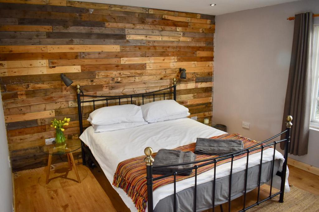 a bedroom with a wooden accent wall and a bed at Ash rock House in Haverfordwest