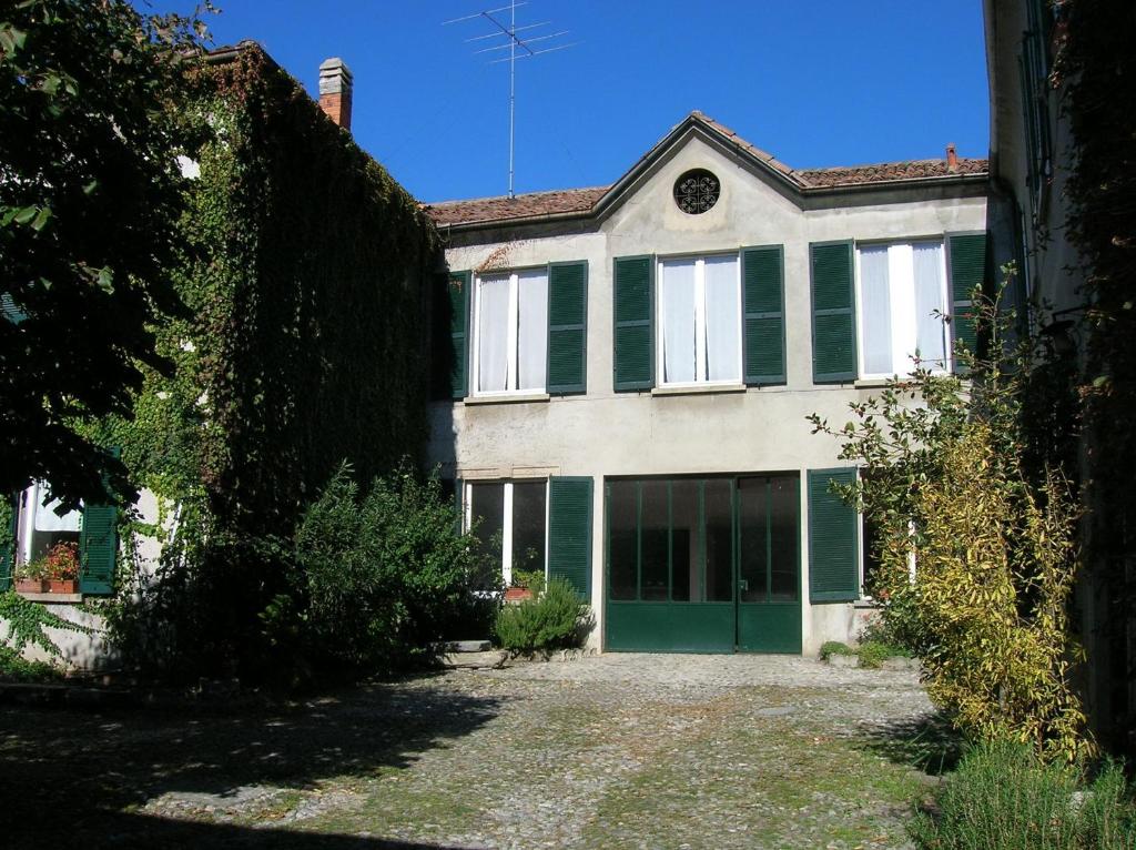 an old house with green shutters and a yard at B&B Leon D'Oro in Pusiano