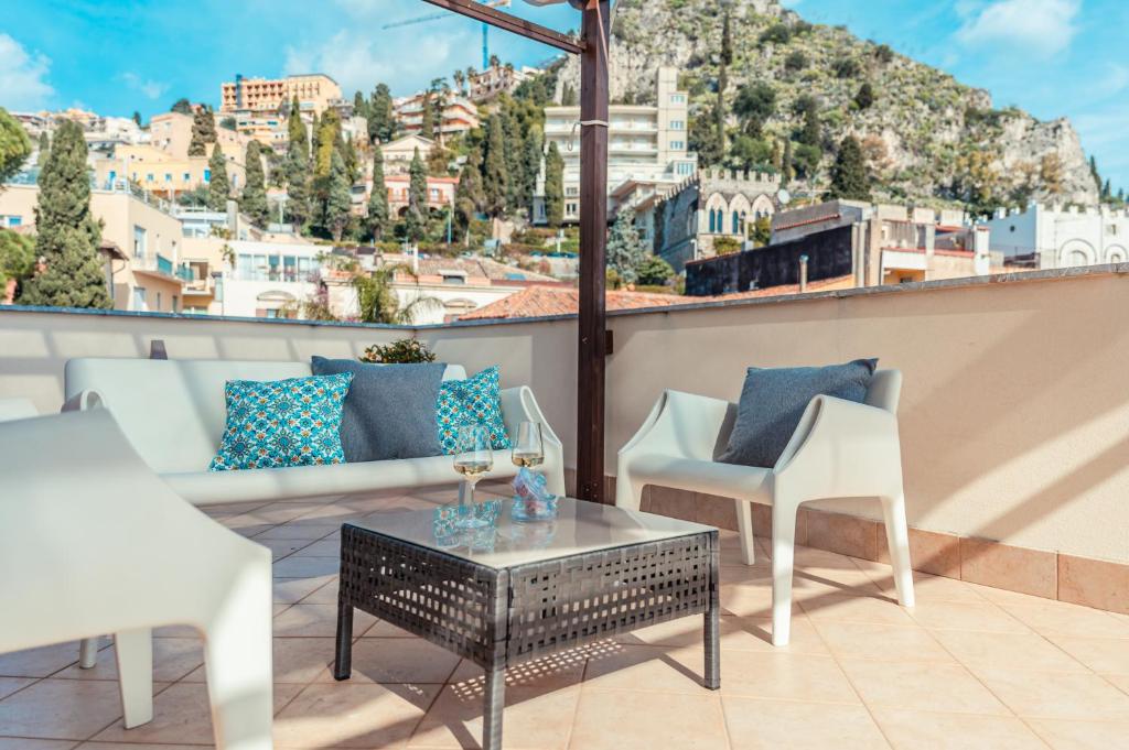 a patio with chairs and a coffee table on a roof at Mosaico Taormina Guest House in Taormina
