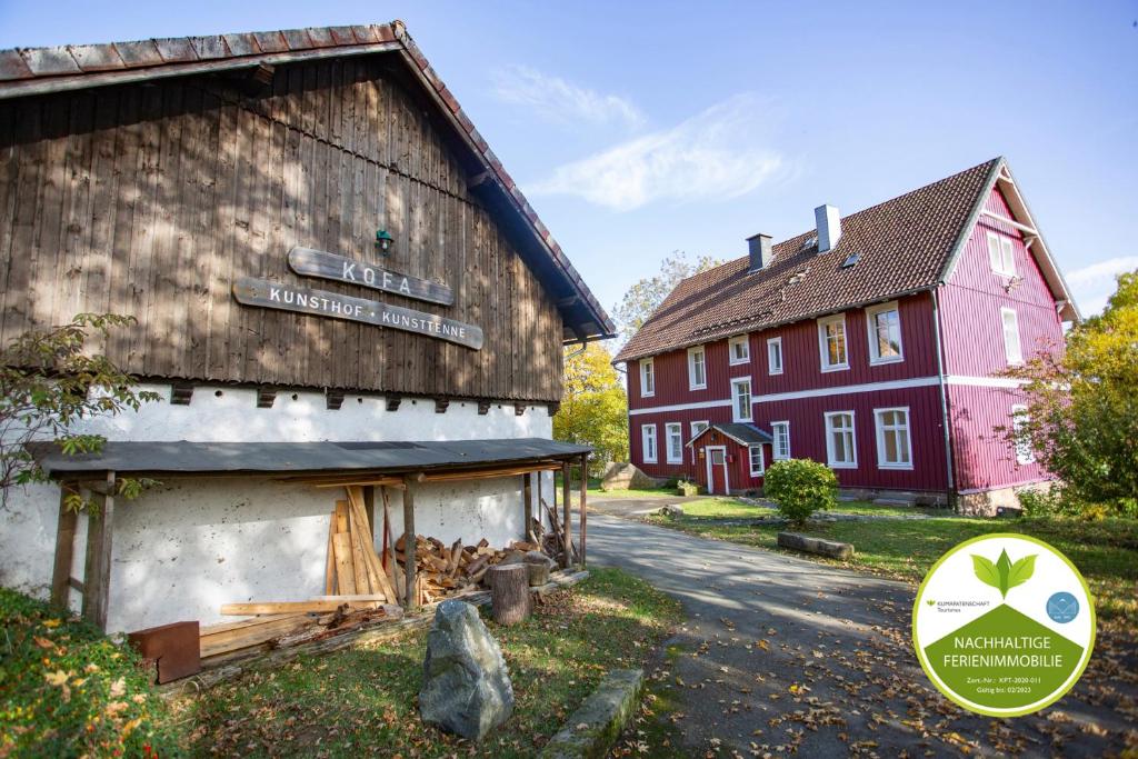 un bâtiment avec un panneau à côté d'une grange rouge dans l'établissement kofa1895 - Königliche Oberförsterei Andreasberg, Apartment 1 - EG, à Sankt-Andreasberg