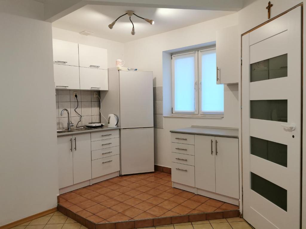 a white kitchen with white cabinets and a window at WHITE Apartment in Jabłonna