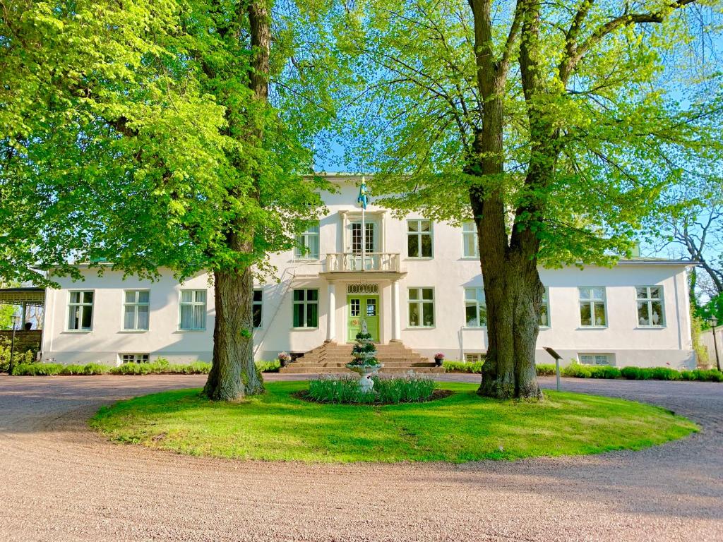 une maison blanche avec des arbres devant elle dans l'établissement Drottning Victorias Hotell & Vilohem, à Borgholm