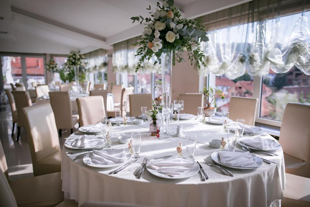 uma mesa com uma toalha de mesa branca e flores sobre ela em Hotel Tami Residence em Niš