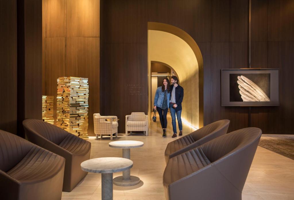 twee mensen lopen door een lobby met stoelen en tafels bij Four Seasons Hotel New York Downtown in New York