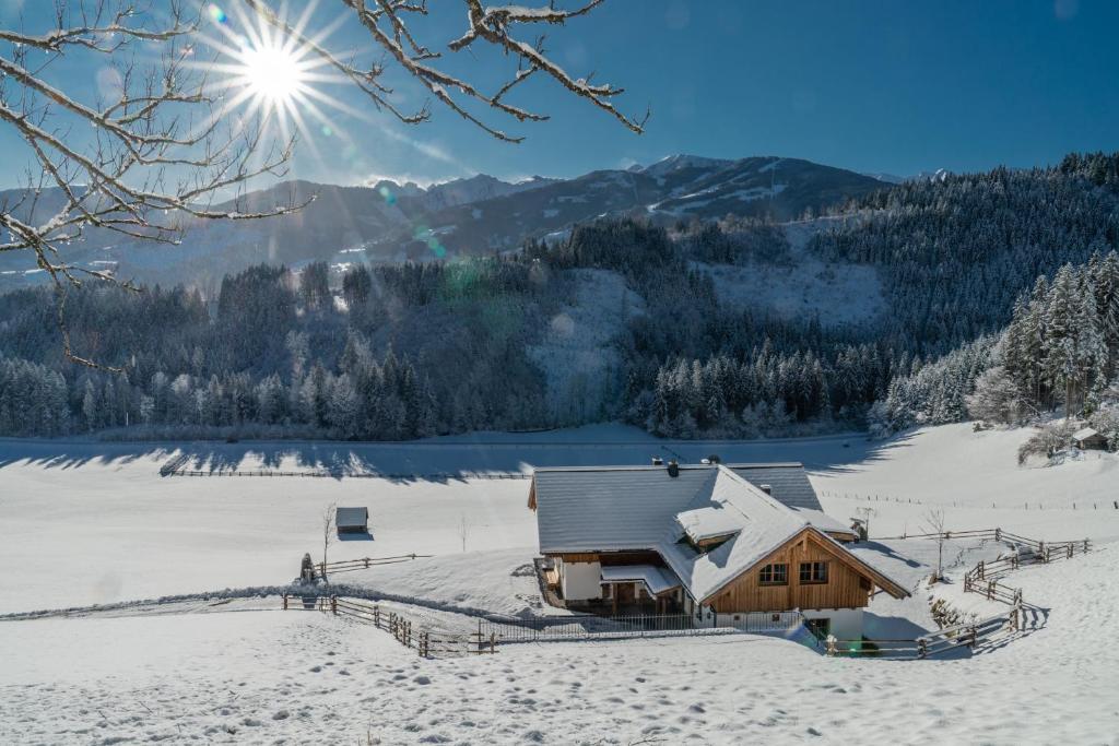 a cabin in the snow with the sun in the sky at Almchalet Linharterhof in Haus im Ennstal