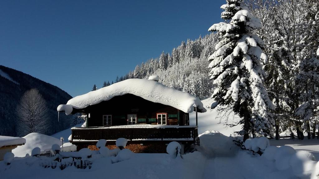 eine schneebedeckte Hütte mit einem schneebedeckten Dach in der Unterkunft Ferienhaus Abendstille in Ramsau am Dachstein