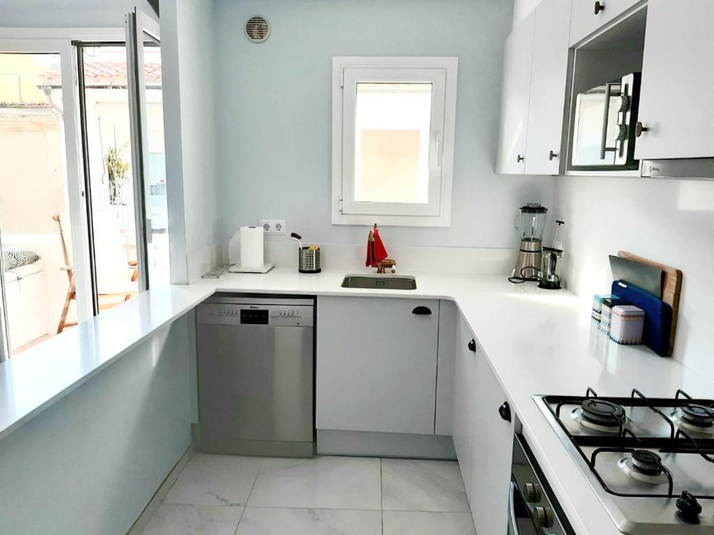 a white kitchen with a sink and a stove at 2 bedroom apartment in the old town, close to the beach in L'Escala