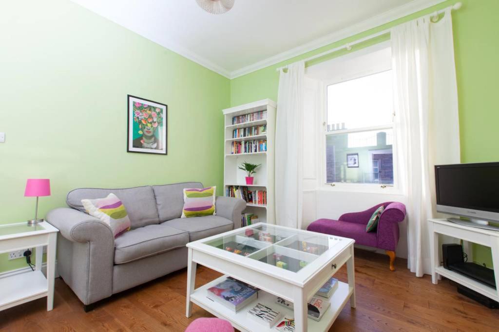 a living room with a couch and a tv at Bright and Modern Causewayside Apartment in Edinburgh