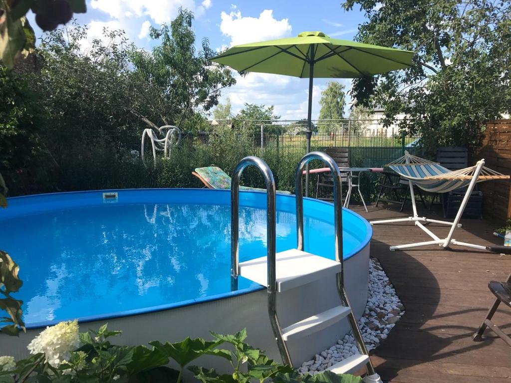 uma piscina com um guarda-sol, uma cadeira e uma mesa em Ferienhaus Hennig em Bersteland