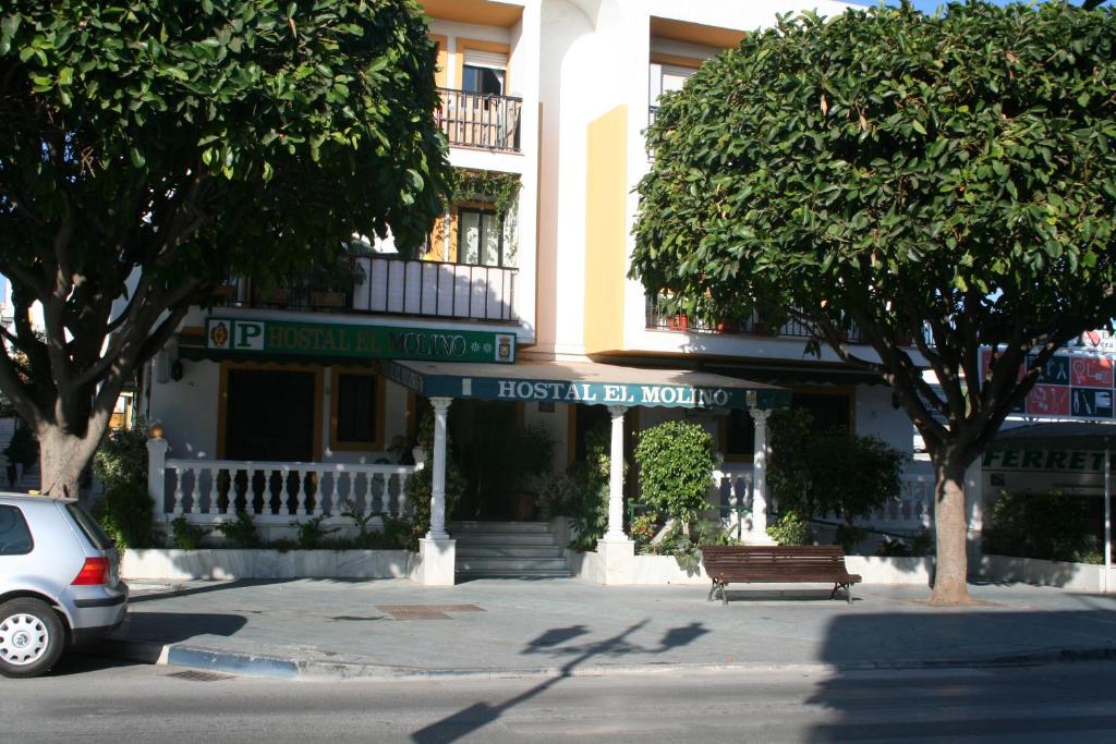 un coche aparcado frente a un edificio con un banco en HOSTAL EL MOLINO, en Marbella