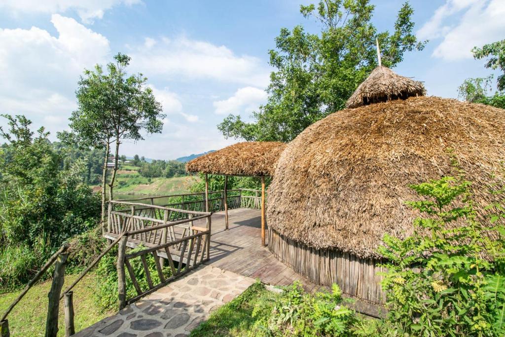 a hut with a thatched roof and a staircase at Byoona Amagara at Lake Bunyonyi in Kabale