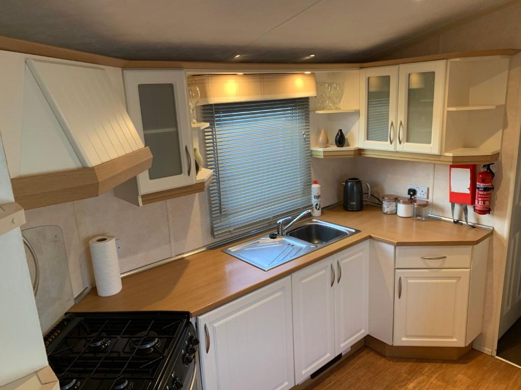a small kitchen with white cabinets and a sink at Chapel Caravans PS12A in Chapel Saint Leonards