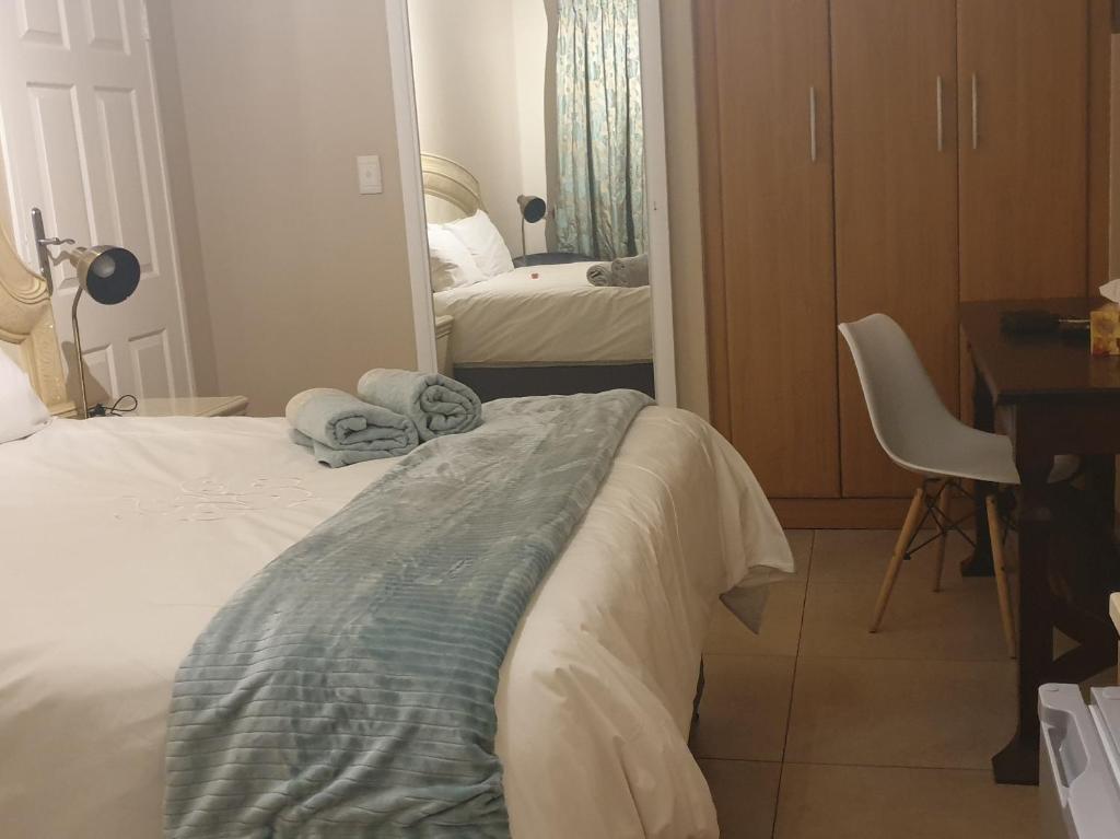 a bedroom with a bed and a desk and a mirror at Langa's Gabedi Goshen in Pretoria