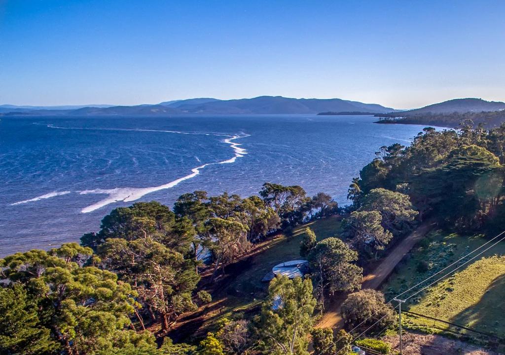 an aerial view of the ocean with trees and a beach at Taylors Bay Cottage in South Bruny