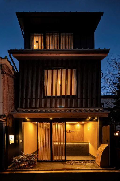 a black building with a lit up facade at night at Connect inn Shichijo-Kamogawa in Kyoto