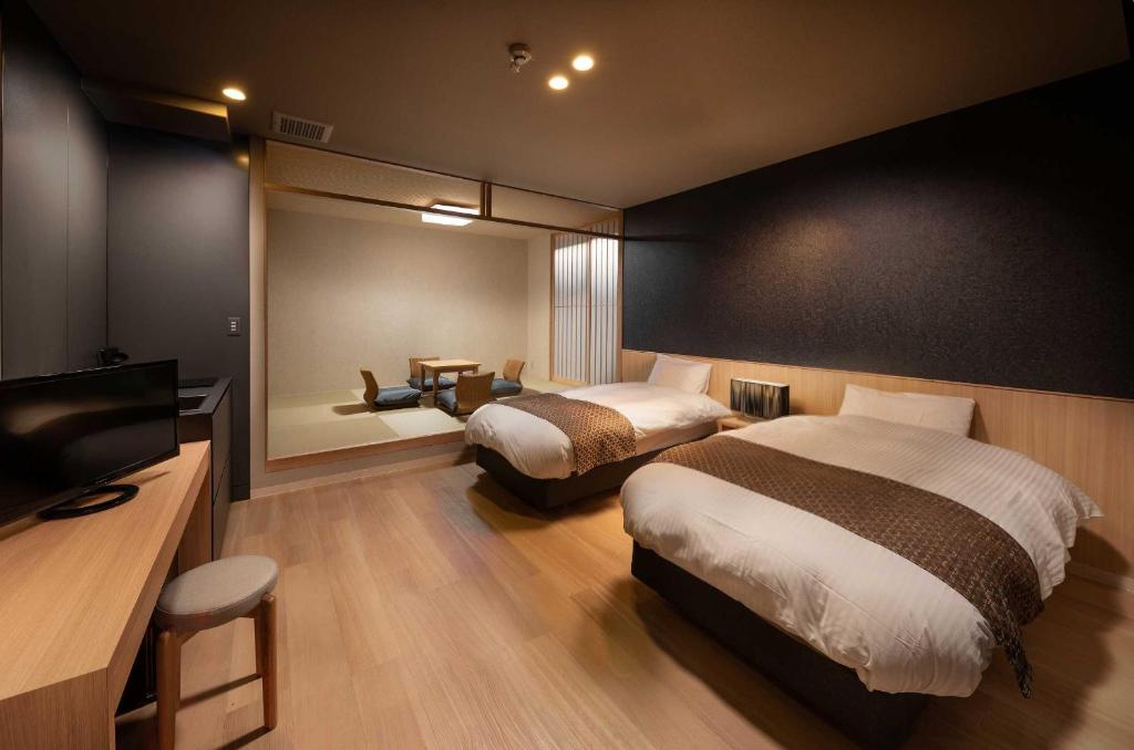 a bedroom with two beds and a flat screen tv at Connect inn Shichijo-Kamogawa in Kyoto