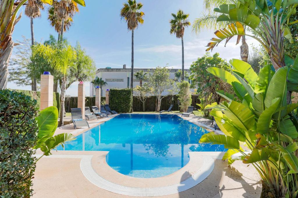 a swimming pool with palm trees and a building at Can Mandol Villa in Inca