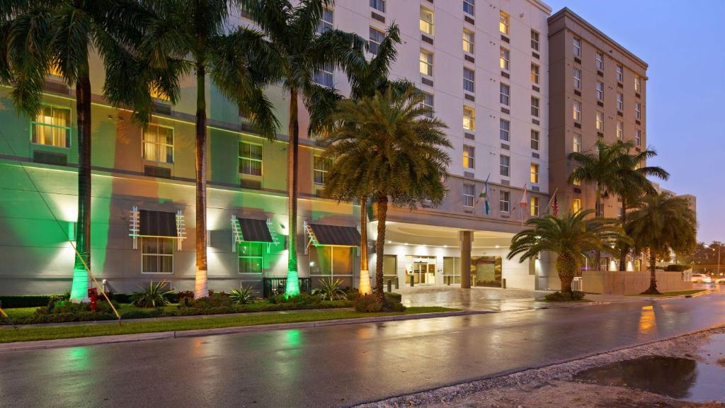 an empty street in front of a building with palm trees at Best Western Plus Miami Intl Airport Hotel & Suites Coral Gables in Miami