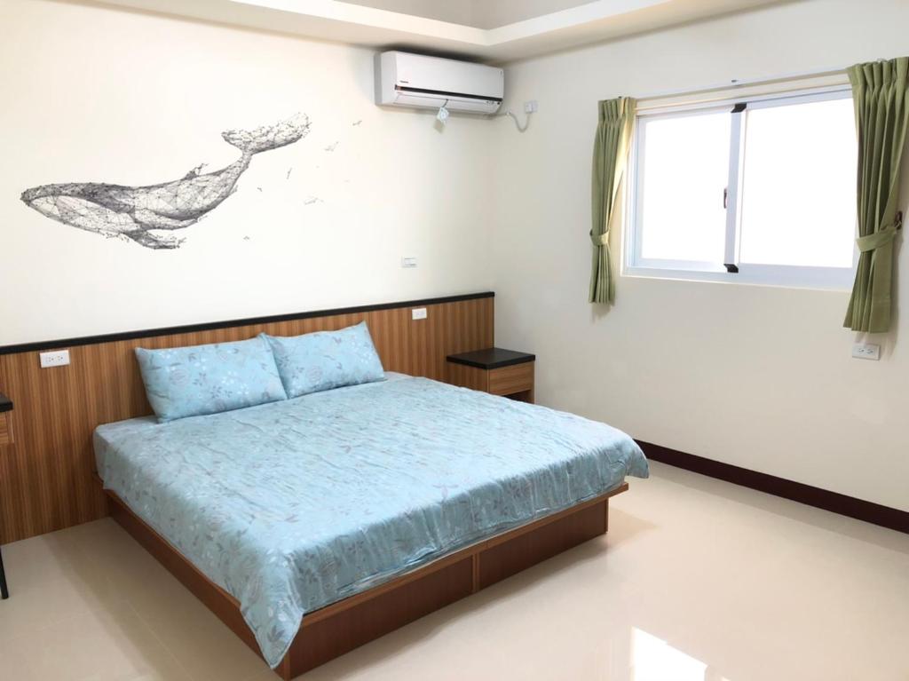 ein Schlafzimmer mit einem Bett und einer Vogelzeichnung an der Wand in der Unterkunft Island House in Magong