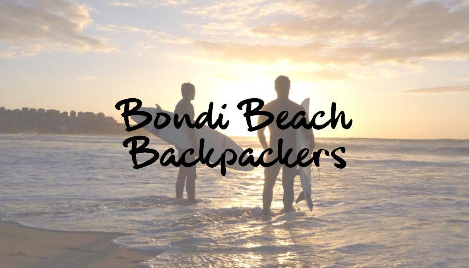 dos personas de pie en el agua en la playa en Bondi Beach Backpackers, en Sídney