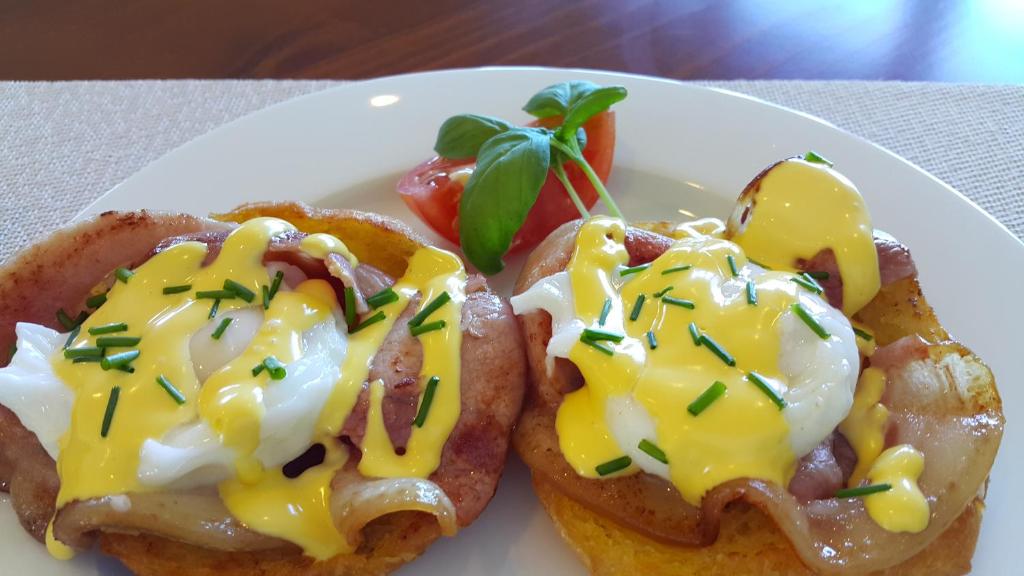 un plato blanco con dos productos de desayuno con huevos y queso en 5 Acres B&B en Tokoroa