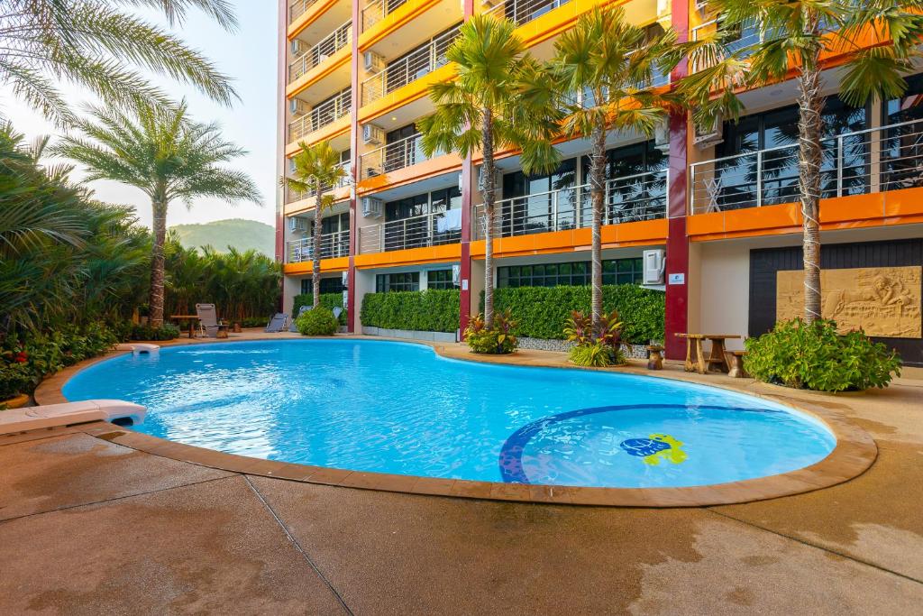 a swimming pool in front of a building with palm trees at NaiHarn Sea Condo by Holy Cow, 1-BR, mountain view in Nai Harn Beach