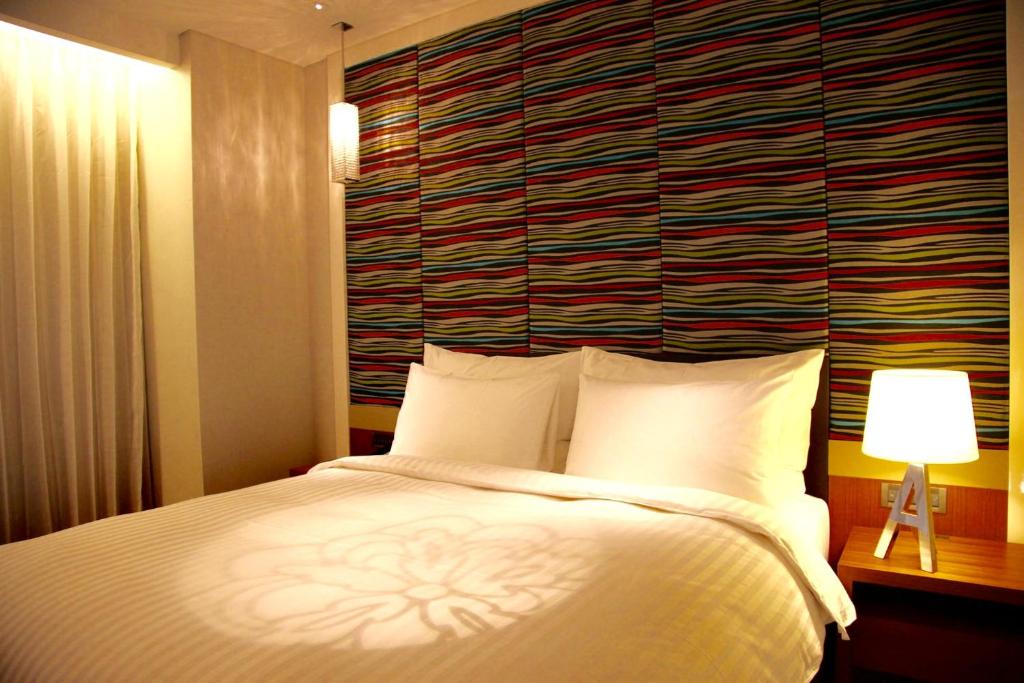 um quarto com uma cama branca e uma parede vermelha em FleurLis Hotel em Hsinchu