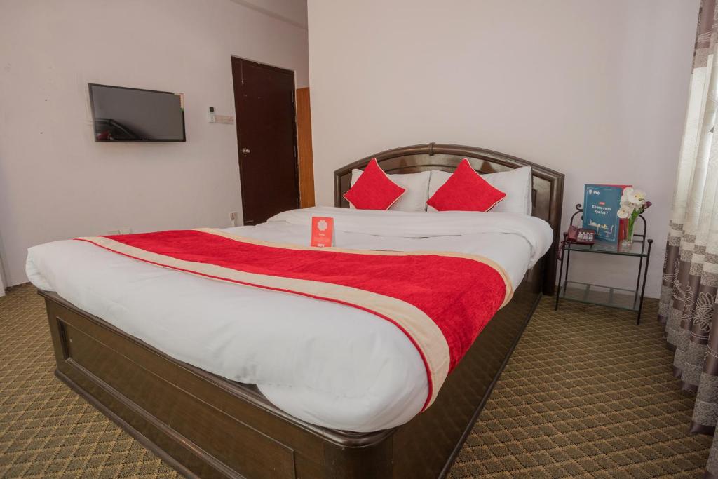 1 dormitorio con 1 cama grande con almohadas rojas en OYO 135 Lost Garden Apartment and Guest House, en Katmandú