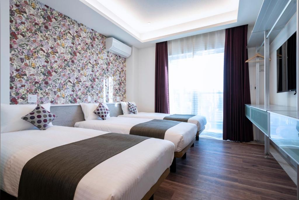 3 Betten in einem Hotelzimmer mit Blumentapete in der Unterkunft Hotel SAILS Asakusa in Tokio