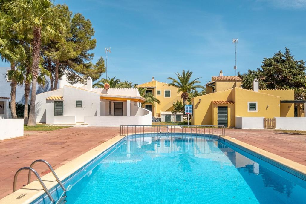 una piscina frente a una casa con palmeras en Son Xoriguer 8, en Son Xoriguer