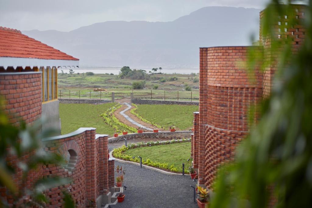 a view of a garden from a brick building at Saj By The Lake, Malshej Ghat in Malshej Ghat