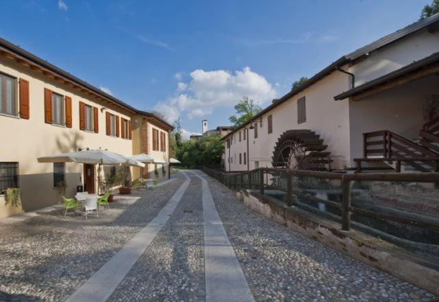 an empty street with buildings and umbrellas on the side at Ostello Molino Di Basso in Roccafranca