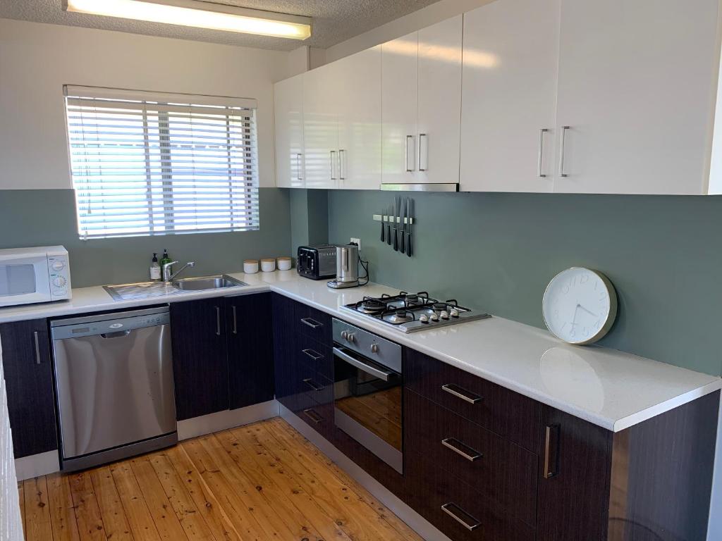 a kitchen with white cabinets and a counter top at 2 Bed Bar Beach Apartment - stroll to beach & cafes, supermarket apartment number 6 in Newcastle